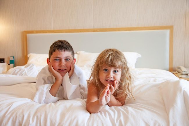 dzieci leżą na łóżku hotelowym
