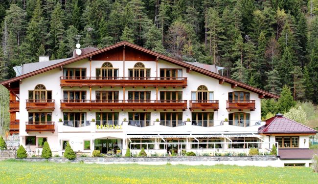 Hotel górski otoczony lasem na tle zielonych zboczy