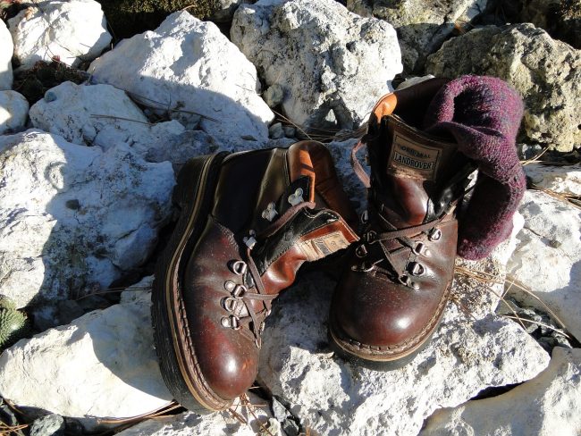 Skórzane buty trekkingowe stojące na kamieniach wśród gór