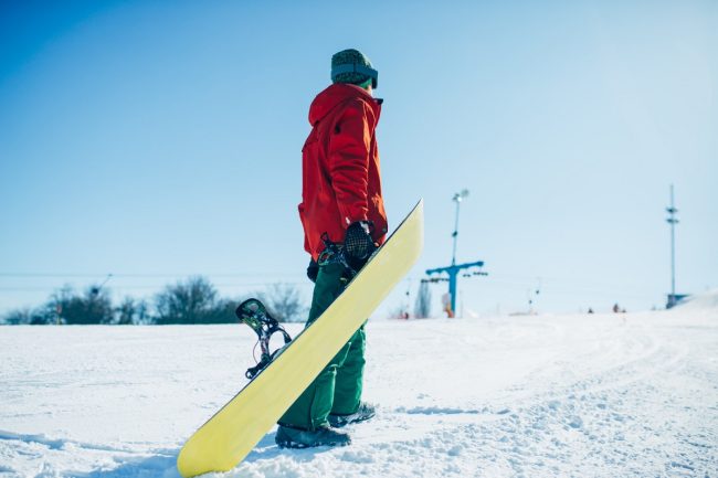 mężczyzna z deską snowboardową na stoku